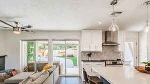A modern kitchen with white cabinets, a central island, and a dining area with a sofa and chairs. - 6 bdrm 5bath in Old Town with Casita, Game Room, and Pool. Two Kitchens!  (Scottsdale)