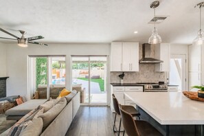 Een moderne keuken met witte kasten, een centraal eiland en een zithoek met een bank en stoelen.
