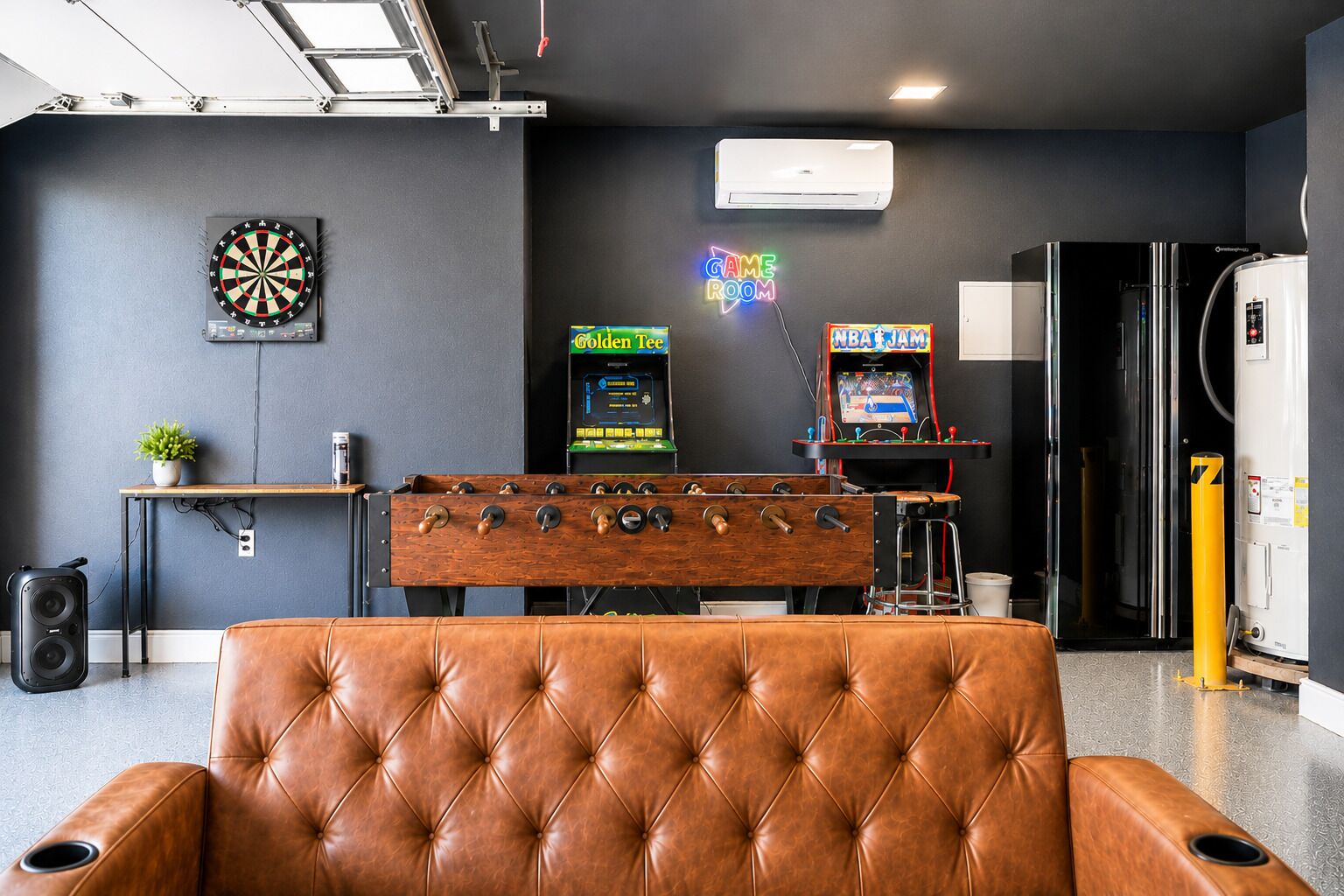 Una habitación con mesa de fútbol de mesa, dardos, aire acondicionado y juegos de arcade.