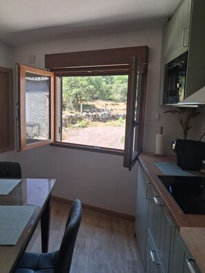 A kitchen with a large window, a dining area with a table and chairs, and a microwave above the counter.