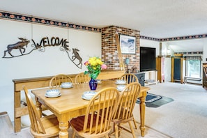 A dining area with a wooden table and chairs, a vase with flowers, and a 'WELCOME' sign with animal decorations. - Walk to Echo Lake State Park! Family Escape (Conway)