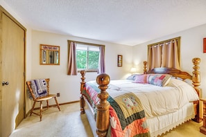 A bedroom with a wooden four-poster bed, a small chair, a window with curtains, and a wall-mounted mirror. - Walk to Echo Lake State Park! Family Escape (Conway)