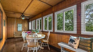 A wooden interior with a dining area, a bench, and large windows.