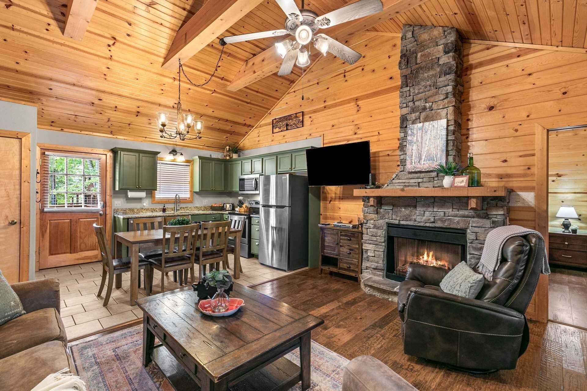 Interior de una cabaña de troncos con comedor, cocina, chimenea y una zona de estar acogedora.