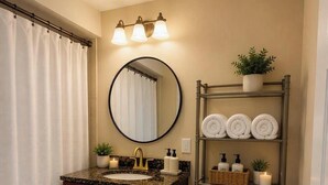 Ein Badezimmer mit Waschtisch, Toilette und einem Regal mit Handtüchern und Pflegeprodukten.