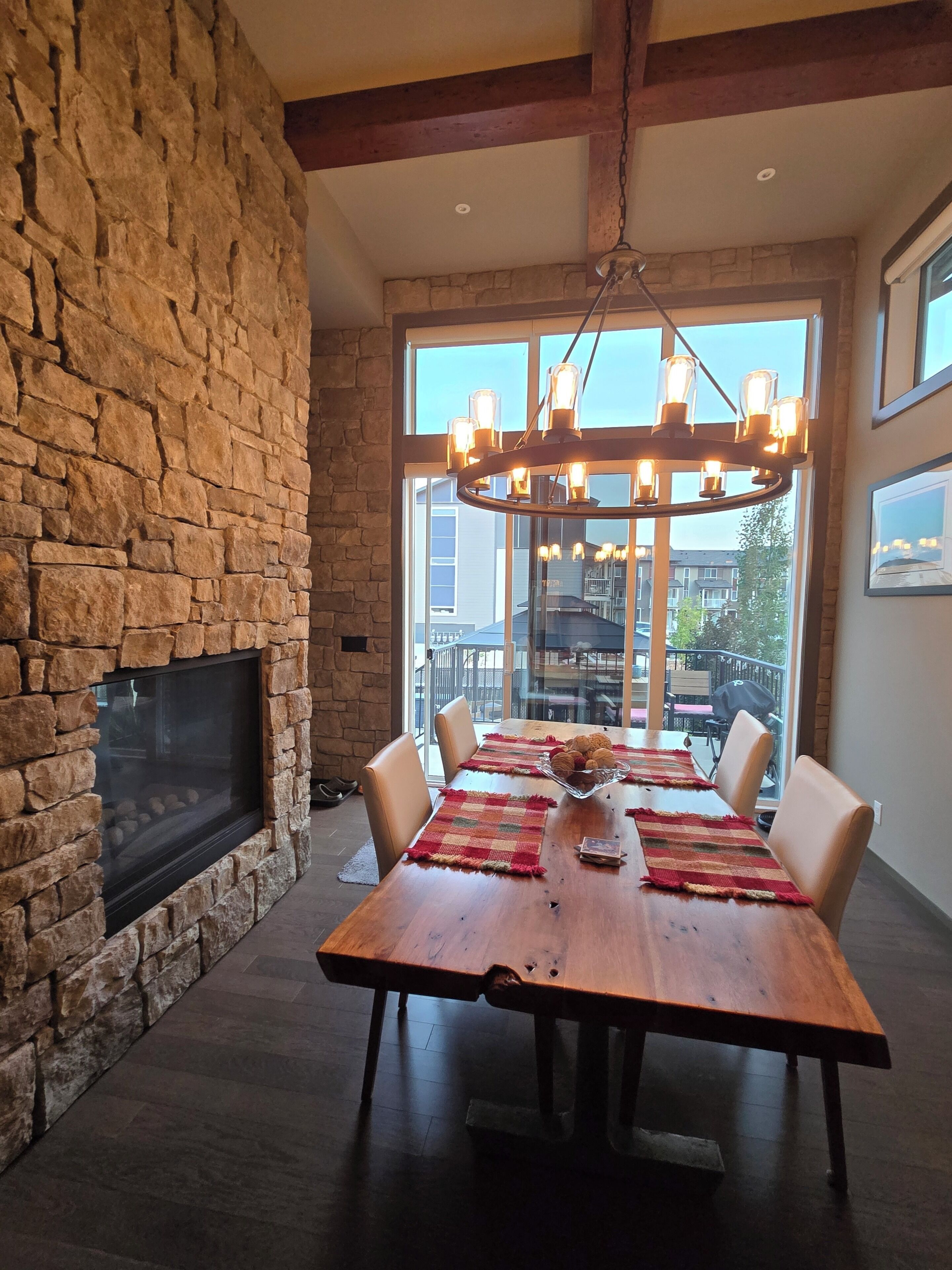 A dining area with a stone wall, a fireplace, and a large window with a city view.