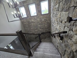 A staircase with stone walls and a metal handrail.