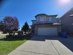A two-story house with a garage, a driveway, and a well-maintained lawn.