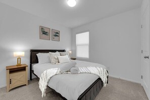 Une chambre à coucher avec un lit, des tables de chevet, une fenêtre et des œuvres d’art murales.
