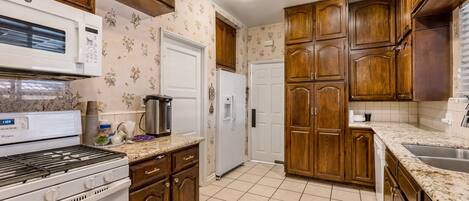 A kitchen with wooden cabinets, a microwave, a stove, and a refrigerator.