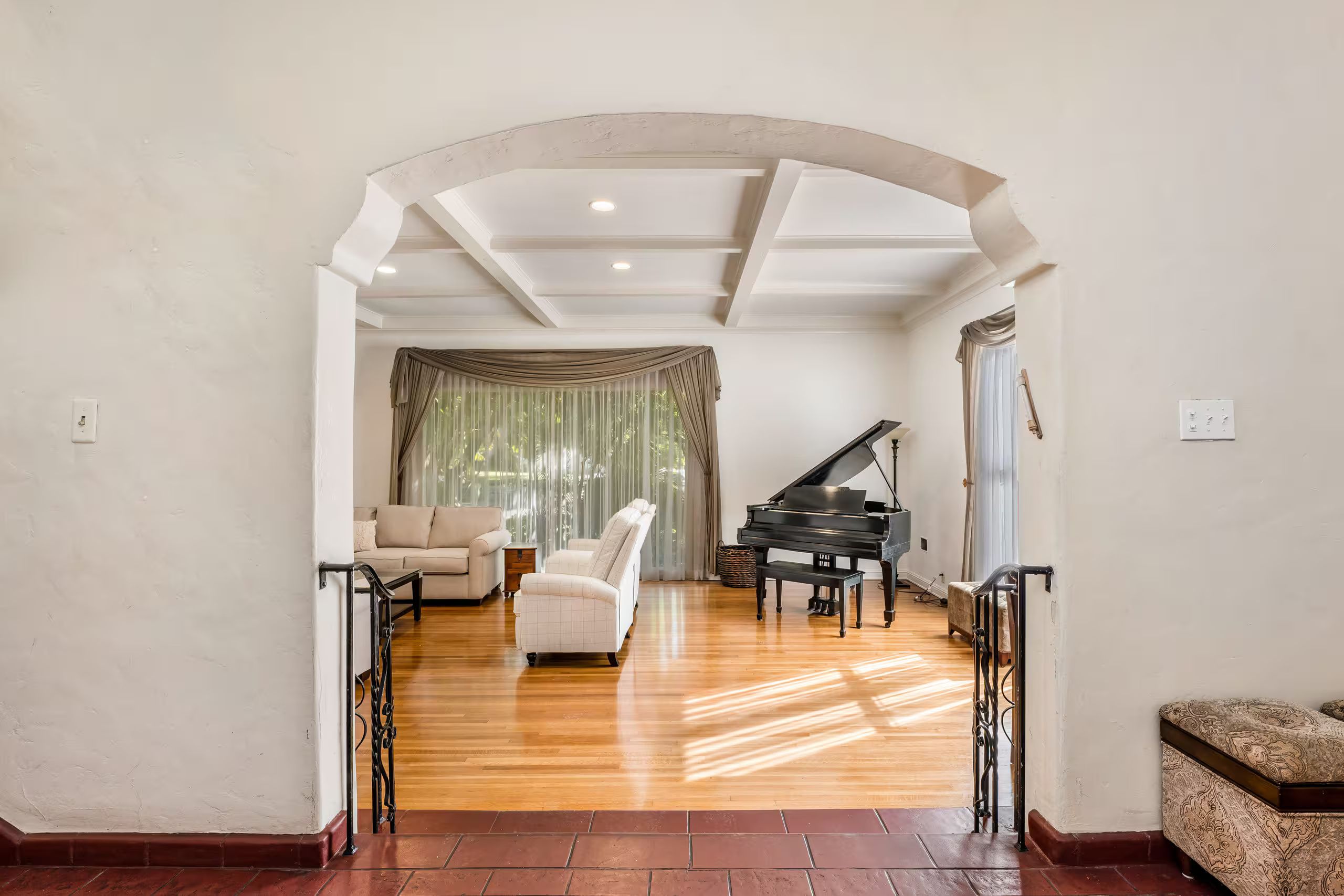 A spacious living room with a grand piano, a sofa, and a staircase leading to another level.