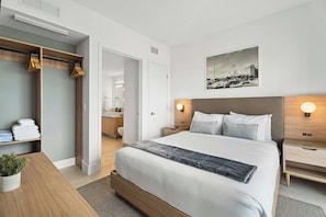 A modern hotel room with a large bed, bedside tables, a wardrobe, and a bathroom visible through an open door. - Paloma Place, Downtown Miami, Pool and Gym (Miami)
