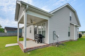 Et etplanshus med en overdækket veranda, garage og sokkel af mursten.