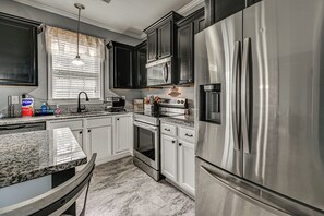 Una cocina moderna con electrodomésticos de acero inoxidable, armarios blancos y encimera de granito.
