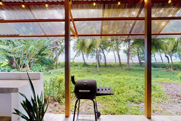 Eine Außenpatio mit Grill, umgeben von üppiger Vegetation und Palmen.