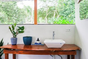 A bathroom with a white sink, a blue vase, and a potted plant on a wooden table. - Oceanfront Open-Air Bungalow on Ballena Beach (Uvita)