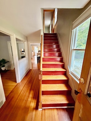 A wooden staircase with a red finish leading to a landing.