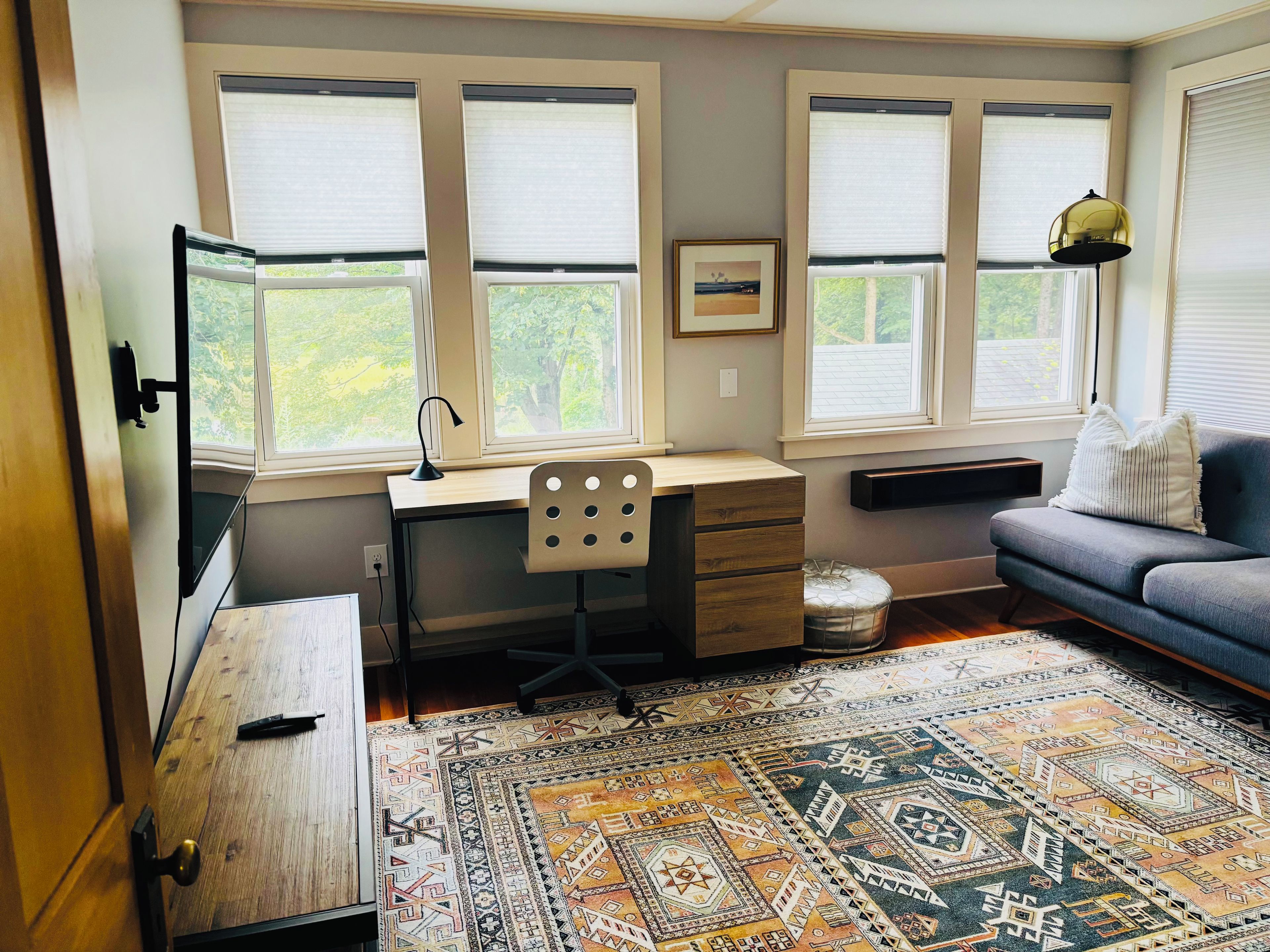 Une pièce comprenant un bureau, une chaise, un canapé et un tapis à motifs.
