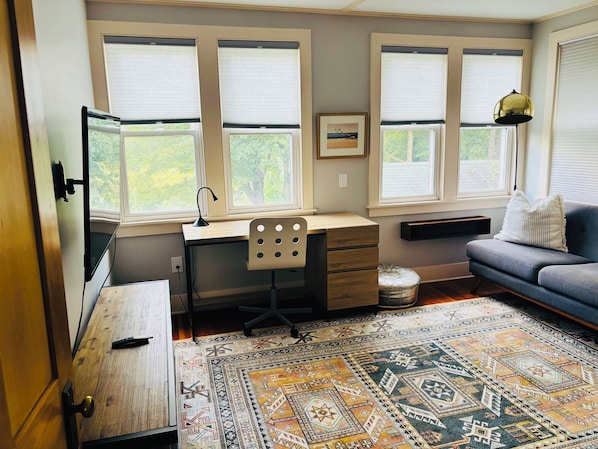 A room with a desk, chair, couch, and a patterned rug.