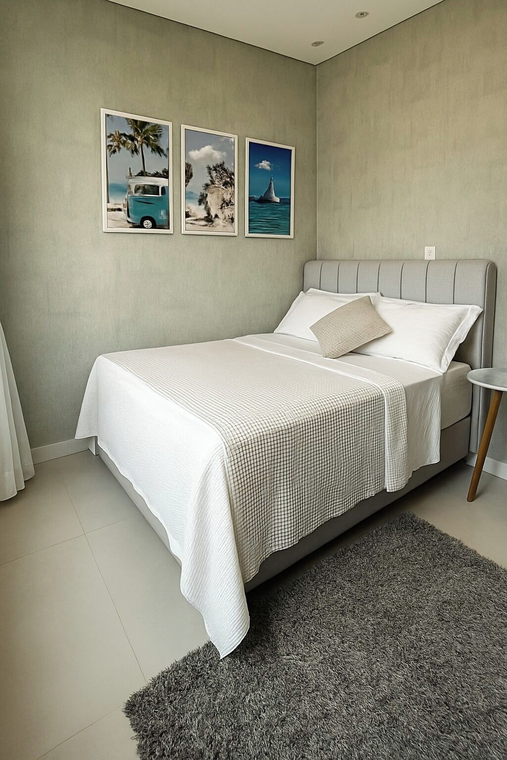 Quarto com cama, mesa de cabeceira, tapete e três quadros na parede.