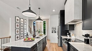 Cozinha moderna com ilha central, eletrodomésticos de aço inoxidável e iluminação pendente.