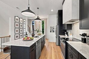 Una cocina moderna con una isla central, electrodomésticos de acero inoxidable e iluminación colgante.