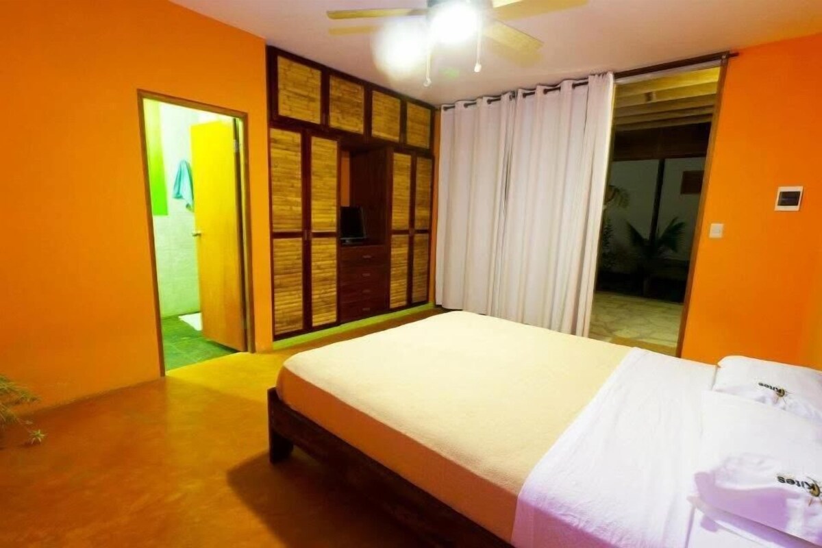 Een slaapkamer met een bed, een plafondventilator en een schuifdeur naar een balkon.