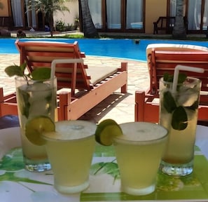 Escena junto a la piscina con sillones de descanso y bebidas.