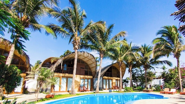 Ein Resort mit Swimmingpool, Palmen und einem Gebäude mit gewölbtem Dach.