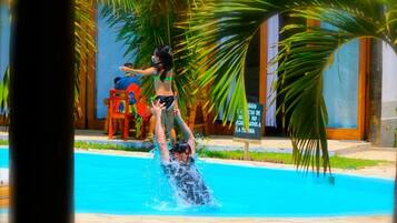Una piscina con alguien nadando y otra persona en el borde.