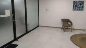 Une pièce avec une porte-fenêtre coulissante, une chaise, un tapis et un tableau au mur.