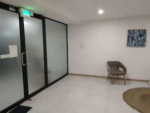 A room with a sliding glass door, a chair, a rug, and a painting on the wall.