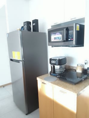A kitchen with a refrigerator, microwave, coffee maker, and a small countertop. - Modern Apartment in San Salvador, Tribeca Urban Living. (San Salvador)
