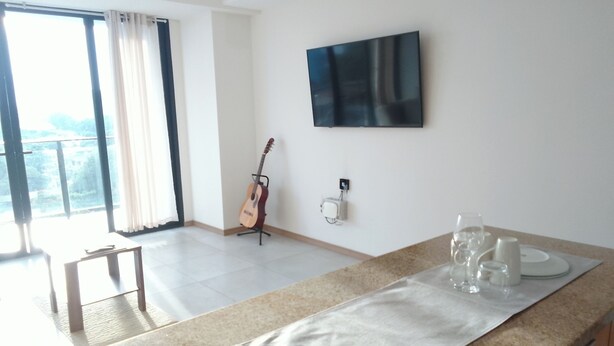 Une cuisine moderne avec un comptoir en granit, un téléviseur à écran plat fixé au mur et une guitare appuyée contre le mur.