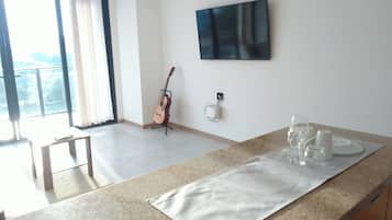 Een moderne keuken met een granieten aanrechtblad, een flatscreen televisie aan de wand en een gitaar die tegen de muur staat.