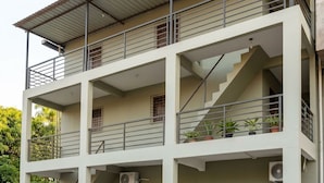 A multi-story building with balconies, a staircase, and a car parked in front.