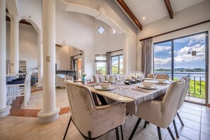 A dining area with a table set for six, large windows with a view of the outdoors, and a modern interior design.