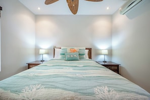 A bedroom with a bed, two bedside lamps, a ceiling fan, and an air conditioning unit. - Ocean-View Retreat! Playa Penca Resort Condo (Playa Penca)