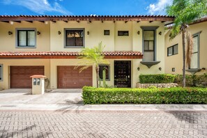 A two-story house with a garage, a small garden, and a paved driveway. - Ocean-View Retreat! Playa Penca Resort Condo (Playa Penca)