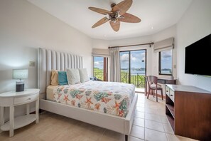 A bedroom with a bed, a desk, a chair, a television, and a balcony with a view. - Ocean-View Retreat! Playa Penca Resort Condo (Playa Penca)