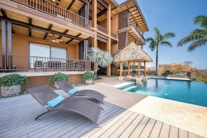Ein Resort mit Pool, Liegestühlen und einem strohgedeckten Pavillon.