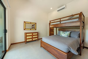 Ein Schlafzimmer mit Etagenbett, einem Holzschrank, einem Spiegel und einer Klimaanlage.