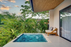 Ein moderner Poolbereich im Freien mit einem klaren, blauen Pool, umgeben von üppiger Bepflanzung und einer Holzpergola.
