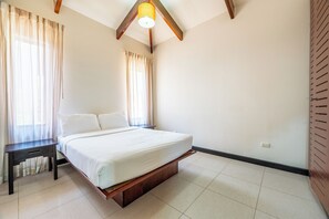A bedroom with a bed, a nightstand, a ceiling light fixture, and a window with curtains.