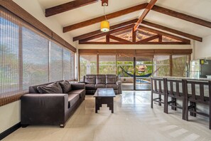 Amplia sala de estar con sofá, mesa de centro y cocina equipada con refrigerador y pileta.