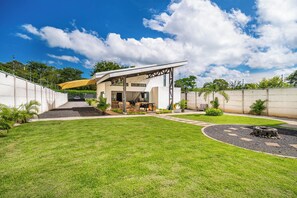 A modern house with a covered patio, a well-maintained lawn, and a fire pit area. - Stylish 'Casa Nonos' Home w/ Yard & Fire Pit! (Playas del Coco)