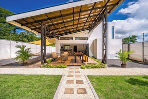 A modern house with a covered patio area, a dining table, and chairs. - Stylish 'Casa Nonos' Home w/ Yard & Fire Pit! (Playas del Coco)