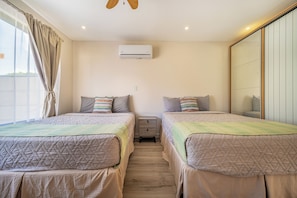 A bedroom with two beds, a wardrobe, a ceiling fan, and an air conditioning unit. - Stylish 'Casa Nonos' Home w/ Yard & Fire Pit! (Playas del Coco)