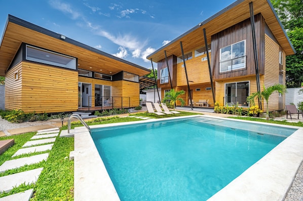 A modern two-story house with a swimming pool, wooden exterior, and a well-maintained garden. - Chic 'Alpinias' Condo w/ Pool Access, Near Beach (Playas del Coco)