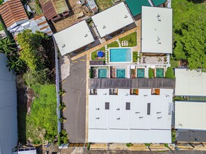 A multi-story building with a rooftop pool, multiple balconies, and a parking area. - Chic 'Alpinias' Condo w/ Pool Access, Near Beach (Playas del Coco)